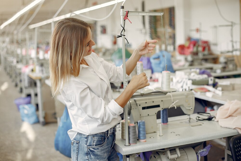 Costureira preparando a linha numa máquina de costura industrial